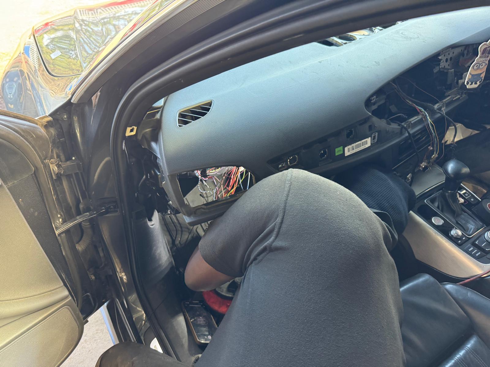 A Godstone Cars mechanic working on wiring under an Audi dashboard